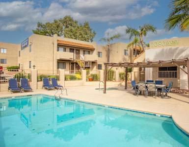 A pool area with chairs and a building in the background.