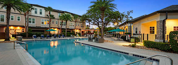 A pool surrounded by palm trees and lounge chairs.