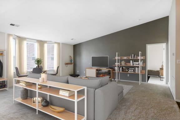 a living room with a gray couch and a tv at Mansions at Delmar, New York, 12054