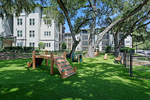 A playground with a slide and a wooden bench is in the foreground of a grassy area.