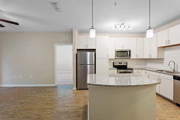 A kitchen with a refrigerator, microwave, and oven.