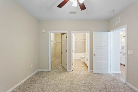 A room with a ceiling fan and three open doors.