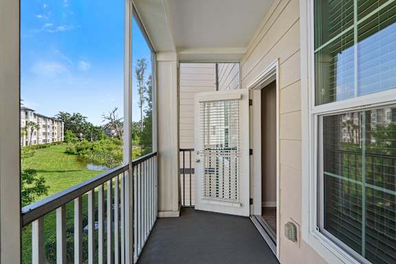 A balcony with a view of a green lawn and buildings.