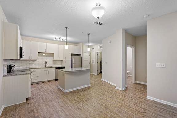 A kitchen with white cabinets and a wooden floor.