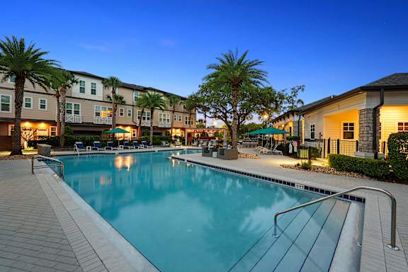 A swimming pool surrounded by palm trees and apartment buildings.