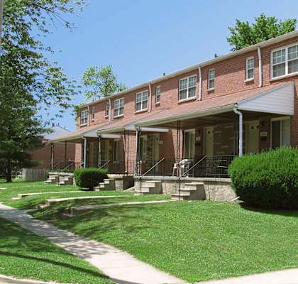 A red brick building with a green bush in front.