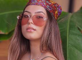 A woman with a colorful headband and sunglasses is posing for a photo.