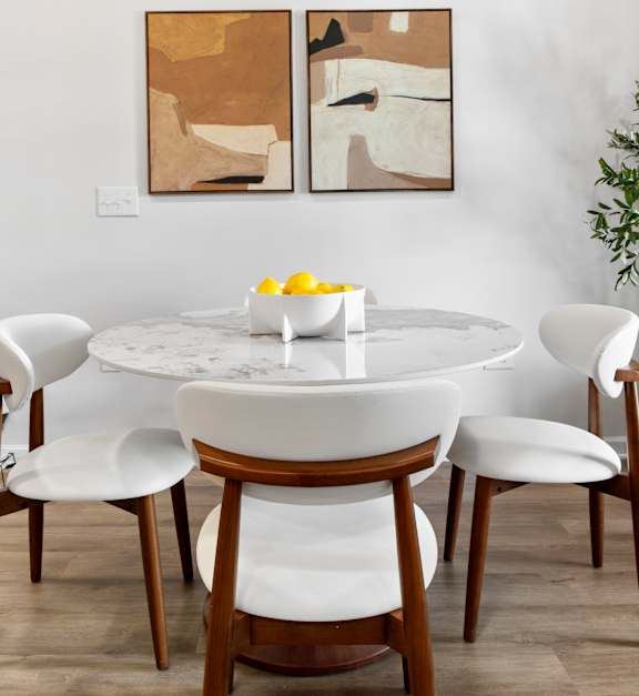 A dining table with chairs and a bowl of lemons on it.