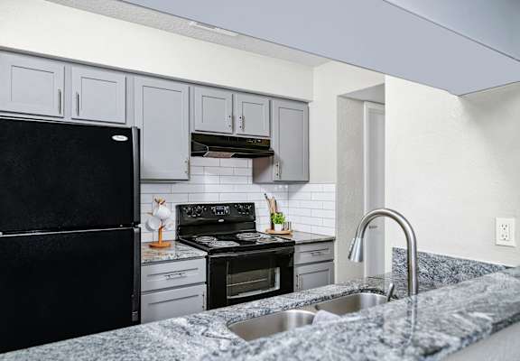 an updated kitchen with granite counter tops and black appliances