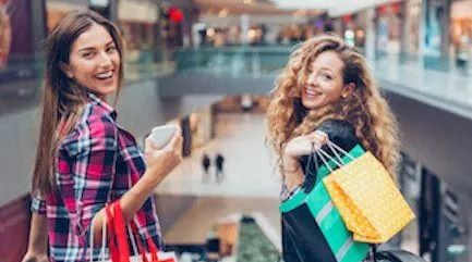 Two women with shopping bags in a mall.