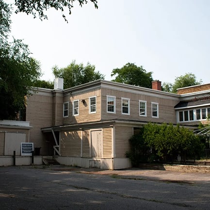 A two-story building with a garage door on the first floor and a balcony on the second floor.