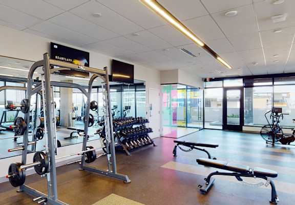 A gym with a variety of equipment including dumbbells and weight machines.