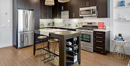 A modern kitchen with dark brown cabinets and stainless steel appliances.