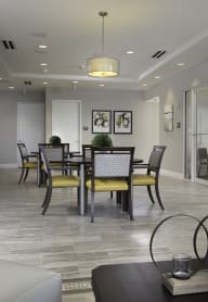 a resident clubhouse with gray walls and a large table with yellow and black chairs