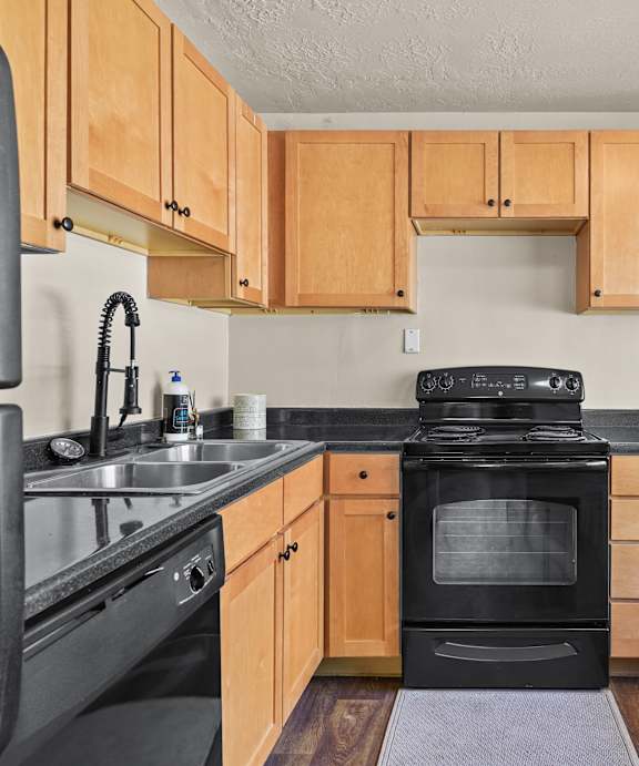 A kitchen with wooden cabinets and black appliances.