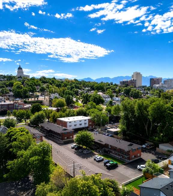 A cityscape with buildings and trees under a blue sky.