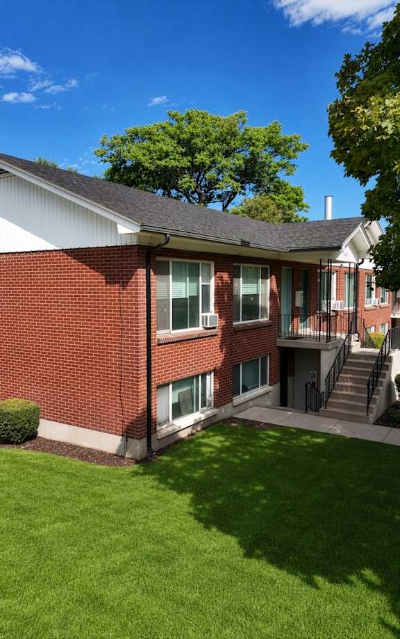 A red brick house with a green lawn in front.