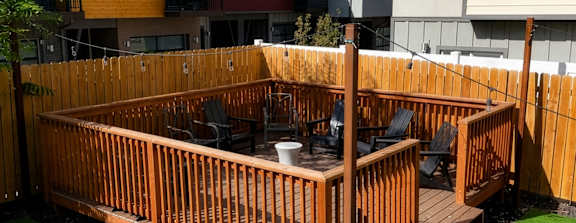 A wooden deck with a hot tub in the middle of a grassy area.