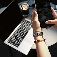 A person is holding a smartphone in one hand and a laptop in the other.