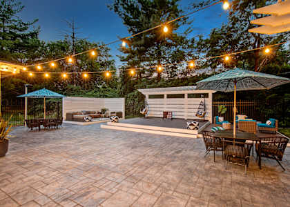 A patio with a table and chairs under a string of lights.