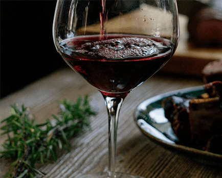 a glass of red wine on a table with food
