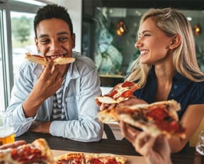 a man and woman eating pizza at a table