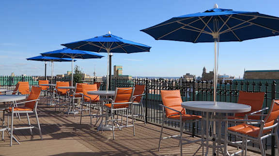 A patio with tables and chairs and umbrellas.