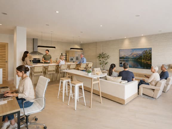 A group of people are gathered in a modern kitchen and living room area.