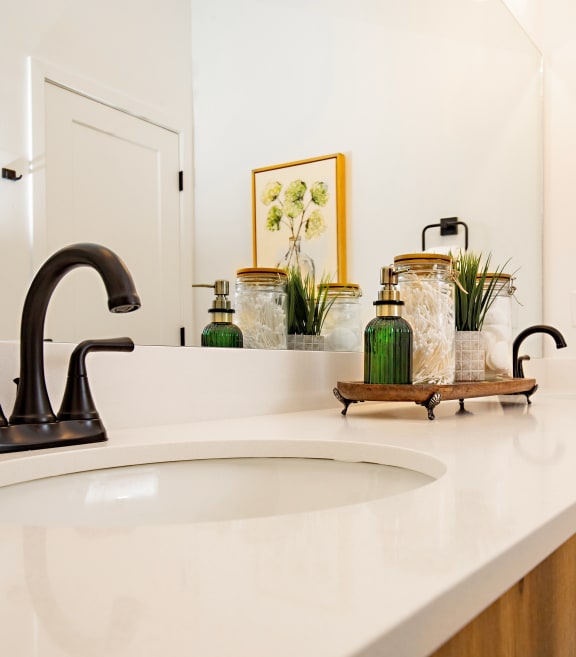 a bathroom with white countertops and a black faucet