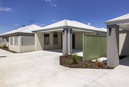 A row of modern houses with white walls and grey roofs.