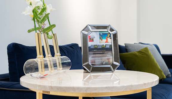 A table with a vase of flowers and a picture frame on it.