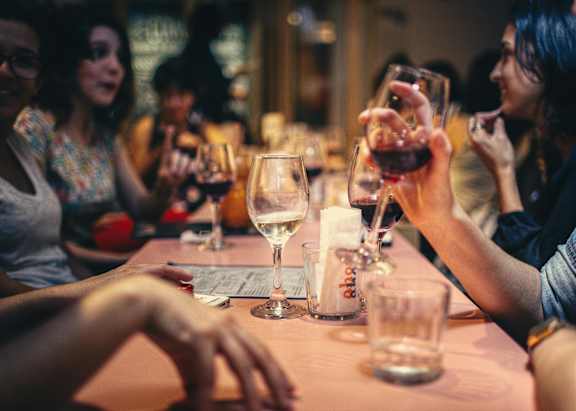 A group of people are sitting around a table with wine glasses in front of them.