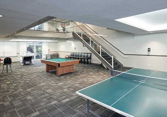 A room with a green table tennis table and a staircase.