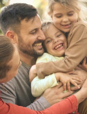 a man and woman hugging their two daughters