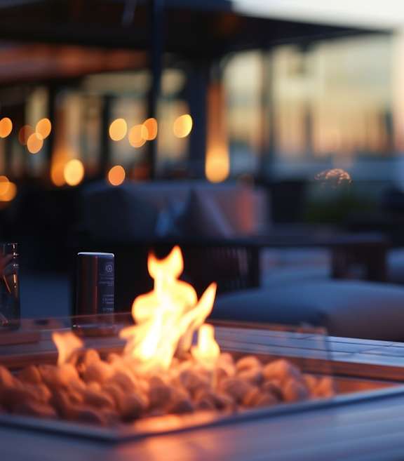 A fire burns in a fire pit on a patio.