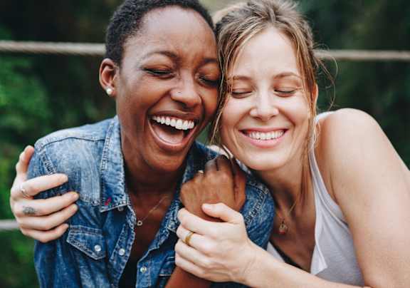 Two women laughing and hugging each other.