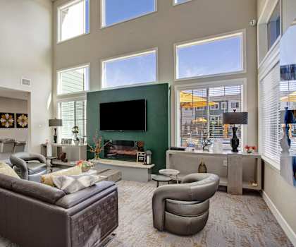 A living room with large windows, a couch and chairs, and a TV at 600 Riverside. 