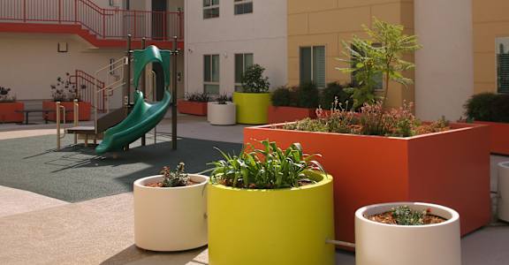 a playground in a courtyard with plants and a slide