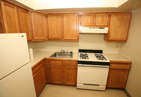an empty kitchen with wooden cabinets and white appliances