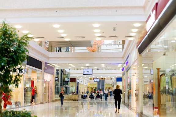 A shopping mall with people walking and stores on either side.