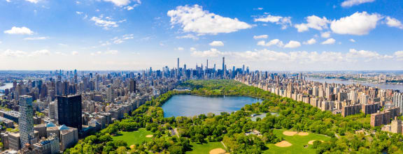 an aerial view of central park with a lake and the nyc skyline