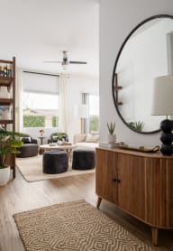 a living room with a large mirror and a wooden dresser