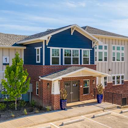 A blue and white house with a brown brick house in front of it.