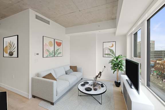 A living room with a couch, a coffee table, and a flat screen TV.