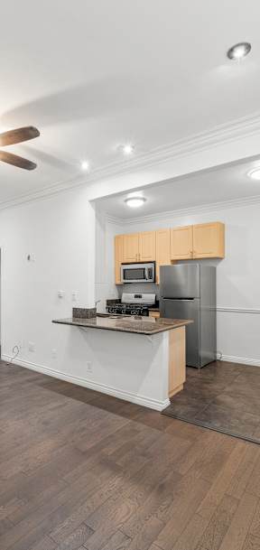 A room with a ceiling fan and a kitchenette.