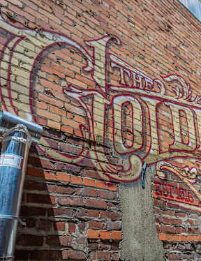 The Old Shoe's sign is on a brick wall.