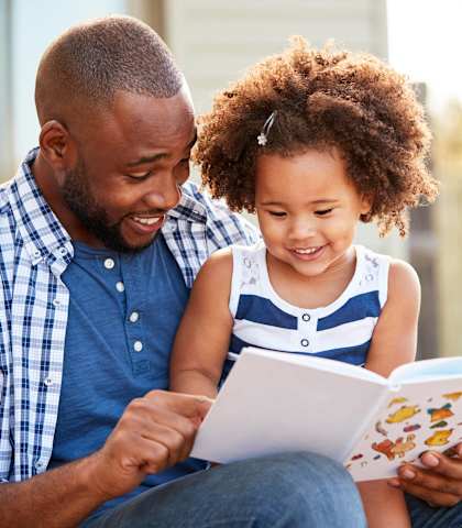 a father and daughter reading a book together