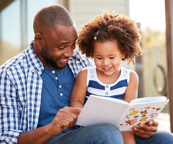 a father and daughter reading a book together