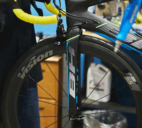 A person is fixing a bicycle wheel with a yellow tire.