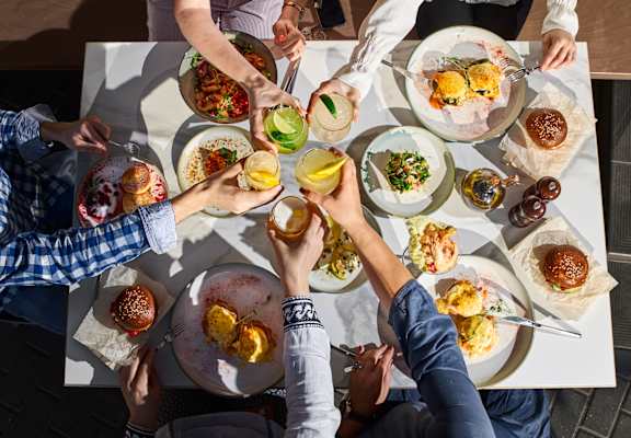 A group of people are sitting around a table with plates of food.